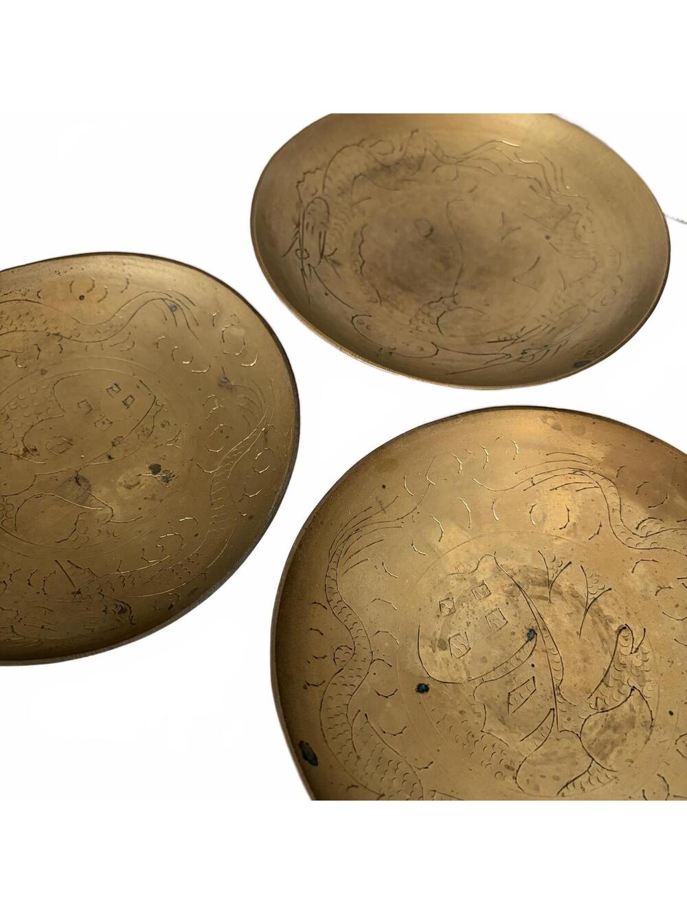 A set of three vintage Chinese etched brass bowls with dragon motifs.